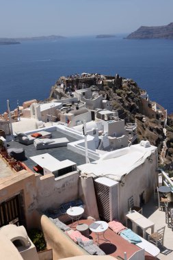 Oia, Santorini, Yunanistan - 3 Temmuz 2021: Yunanistan 'ın Santorini kentindeki Caldera uçurumunun kıyısındaki Agios Nikolaos Kalesi' nin kalıntıları ve Beyazyıkanmış binalar