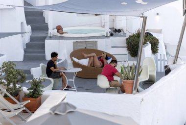 Oia, Santorini, Yunanistan - 28 Haziran 2021: Yunanistan 'ın Santorini adasında, Oia' da teras ve havuzlu ve güzel manzaralı beyazlatılmış dairelerde tam rahatlama