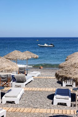 Kamari, Santorini, Yunanistan - 30 Haziran 2021: Santorini 'deki siyah volkanik Kamari plajında güneşlik. Cyclades, Yunanistan