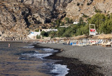 Kamari, Santorini, Yunanistan - 3 Temmuz 2021: Santorini 'deki siyah volkanik Kamari plajında güneşlik. Cyclades, Yunanistan