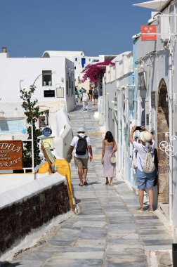 Oia, Santorini, Greece - July 3, 2021: Tourists while walking through the narrow streets of Oia, Santorini, Greece