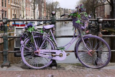 Amsterdam, Hollanda - 21 Nisan 2023: De Wallen köprüsündeki eski lavanta renkli bisiklet - 