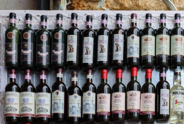 Monteriggioni, İtalya - 17 Eylül 2022: Siena yakınlarındaki Monteriggioni 'de bir şarap dükkanında düzenli olarak düzenlenmiş Chianti Classico şarabı şişeleri. İtalya