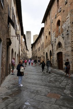 San Gimignano, İtalya - 17 Eylül 2022: Ortaçağ 'ın San Gimingnano kentindeki Via San Giovanni' de turist kalabalığı. Toskana, İtalya