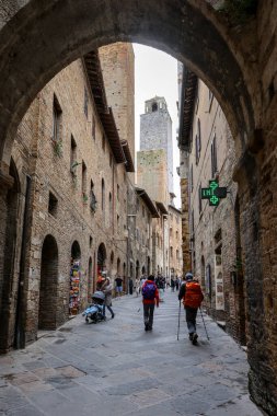 San Gimignano, İtalya - 17 Eylül 2022: Ortaçağ 'ın San Gimingnano kentindeki Via San Mateo' da turistler. Toskana, İtalya