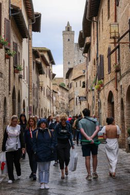 San Gimignano, İtalya - 17 Eylül 2022: Ortaçağ 'ın San Gimingnano kentindeki Via San Giovanni' de turist kalabalığı. Toskana, İtalya