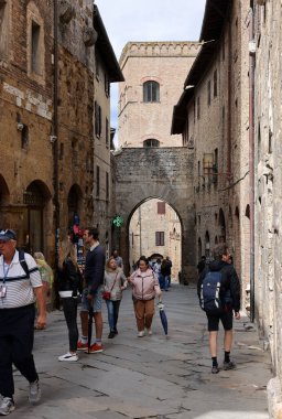 San Gimignano, İtalya - 17 Eylül 2022: Ortaçağ 'ın San Gimingnano kentindeki Via San Mateo' da turistler. Toskana, İtalya