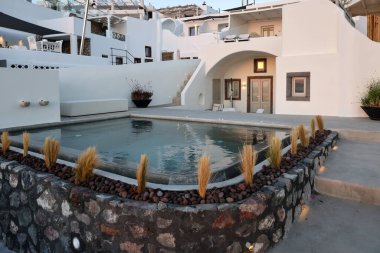 İmerovigli, Santorini, Yunanistan - 29 Haziran 2021: Yunanistan 'ın Santorini adasındaki Imerovigli adasında teraslı ve havuzlu beyaz boyalı evler ve güzel bir manzara 