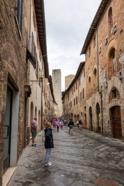 San Gimignano, İtalya - 17 Eylül 2022: Ortaçağ 'ın San Gimingnano kentindeki Via San Giovanni' de turist kalabalığı. Toskana, İtalya