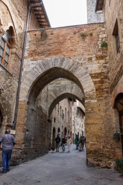 San Gimignano, İtalya - 17 Eylül 2022: Ortaçağ 'ın San Gimingnano kentindeki Via San Mateo' da turistler. Toskana, İtalya