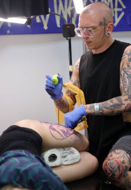 Krakow, Poland -  June 12, 2022: Unidentified  participant at 15th Tattoofest Convention in Cracow. One of the most prestigious tattoo festivals. Tattoo artist at work. 