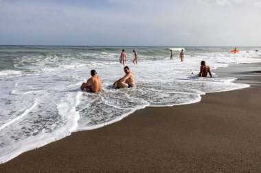 Torremolinos, İspanya - 14 Eylül 2023: Köpüklü deniz dalgaları ve insanları Torremolinos, Malaga, Costa del Sol, İspanya 'daki kumlu Bajondillo sahillerinde rahatlatıyor