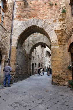 San Gimignano, İtalya - 17 Eylül 2022: Ortaçağ 'ın San Gimingnano kentindeki Via San Mateo' da turistler. Toskana, İtalya