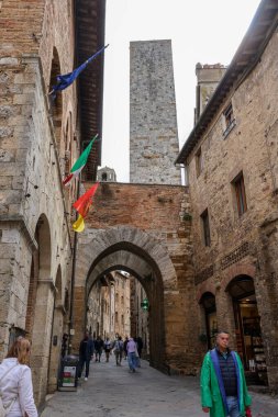 San Gimignano, İtalya - 17 Eylül 2022: Ortaçağ 'ın San Gimingnano kentindeki Via San Mateo' da turistler. Toskana, İtalya