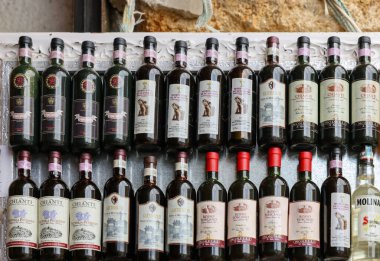 Monteriggioni, İtalya - 17 Eylül 2022: Siena yakınlarındaki Monteriggioni 'de bir şarap dükkanında düzenli olarak düzenlenmiş Chianti Classico şarabı şişeleri. İtalya