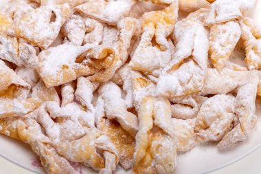 Melek kanatları (Faworki), kekler. Kızarmış tatlı ve üzerine pudra şekeri serpiştirilmiş.