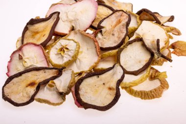 Beyaz bir arka planda izole edilmiş bir yığın kuru armut ve elma. Sağlıklı çiğ vejetaryen tatlı ve ekşi meyveli cipslerden yer.