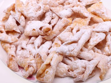 Melek kanatları (Faworki), kekler. Kızarmış tatlı ve üzerine pudra şekeri serpiştirilmiş.