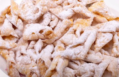 Melek kanatları (Faworki), kekler. Kızarmış tatlı ve üzerine pudra şekeri serpiştirilmiş.