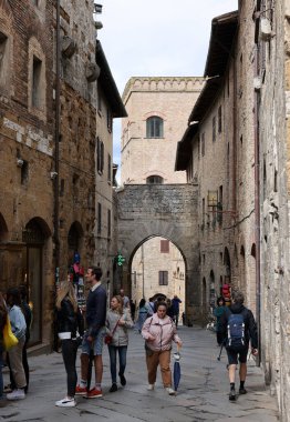 San Gimignano, İtalya - 17 Eylül 2022: Ortaçağ 'ın San Gimingnano kentindeki Via San Mateo' da turistler. Toskana, İtalya