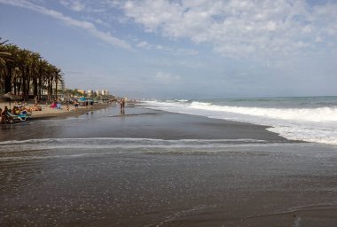 Torremolinos, İspanya - 14 Eylül 2023: Köpüklü deniz dalgaları ve insanları Torremolinos, Malaga, Costa del Sol, İspanya 'daki kumlu Bajondillo sahillerinde rahatlatıyor