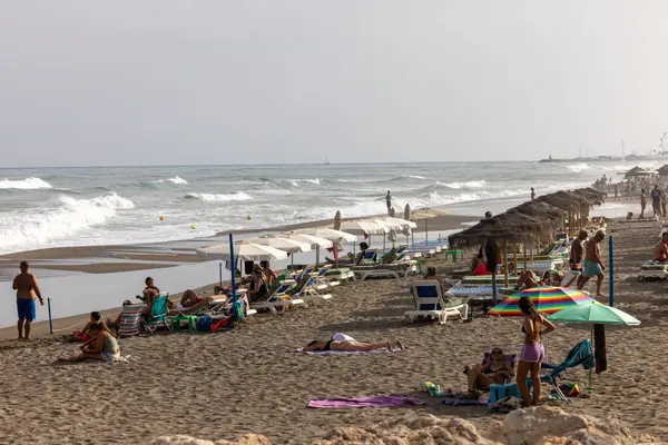 Torremolinos, İspanya - 14 Eylül 2023: Köpüklü deniz dalgaları ve insanları Torremolinos, Malaga, Costa del Sol, İspanya 'daki kumlu Carihuela sahillerinde rahatlatıyor