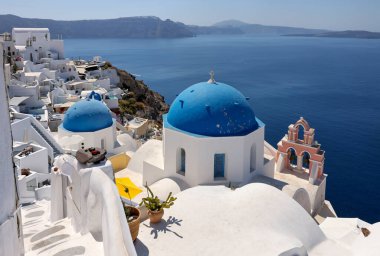 Oia, Santorini, Yunanistan - 3 Temmuz 2021: Yunan ortodoks Hıristiyan kilisesinin mavi kubbesine sahip Oia köyü perspektifinden bakın. Santorini, Yunanistan