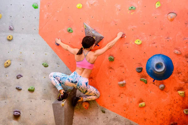 Young Woman Climber Bouldering in Climbing Gym. Extreme Sport and Indoor Climbing Concept.