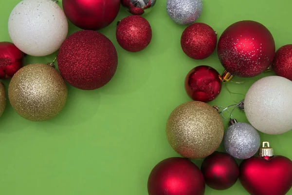 Fotokopi alanı olan yeşil arka planda çeşitli renklerde Noel ağacı süslemeleri. Yeni yıl sahne ayarları.
