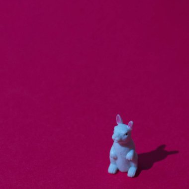 Kırmızı arka planda, fotokopi alanı olan beyaz bir tavşan. Minimalist bir Çin Yeni Yıl kompozisyonu.