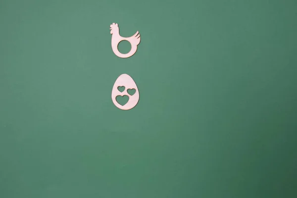 stock image A laying hen and an egg with hearts on a green background with copy space. Minimal flat lay Easter scene.