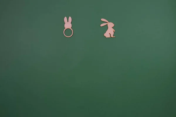Bunny ears and Easter bunny in the bottom on a green background with copy space. Minimal flat lay Easter scene.