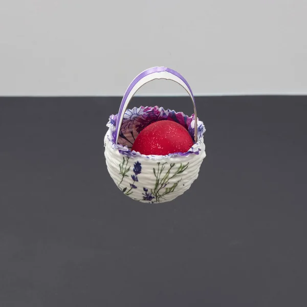 Easter egg in Easter basket floating on black and white background with copy space. Minimal Easter scene.