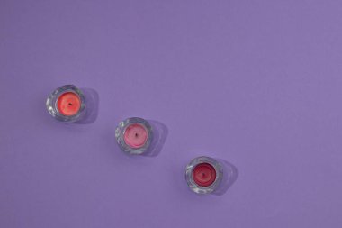 Fotokopi alanı olan mor bir zemin üzerine dizilmiş renkli mumlarla dolu üç cam şamdan. En küçük sahne dekoru.