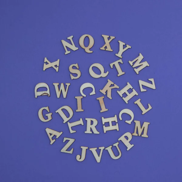紫色の背景に円状に配置されたアルファベットの様々な木製の文字 ミニマルな美景 — ストック写真