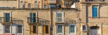 Malta 'da geleneksel ev işleri. Kireçtaşı sarısı tuğlalar ve renkli balkonlar, pencereler