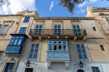 Malta 'da geleneksel ev işleri. Kireçtaşı sarısı tuğlalar ve renkli balkonlar, pencereler