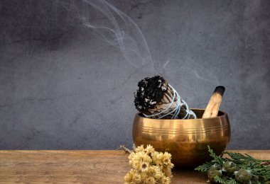 white sage incense and singing bowl in front of white background