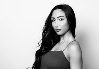 Uzun, parlak siyah saçlı güzel bir kadın. Gülümseyerek poz veriyor.