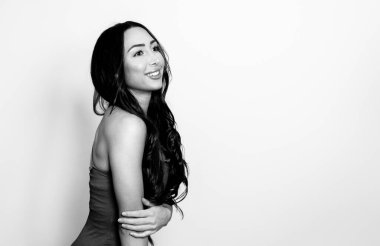 Uzun, parlak siyah saçlı güzel bir kadın. Gülümseyerek poz veriyor.