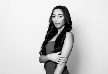 Uzun, parlak siyah saçlı güzel bir kadın. Gülümseyerek poz veriyor.