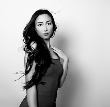 Uzun, parlak siyah saçlı güzel bir kadın. Gülümseyerek poz veriyor.