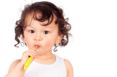 Kıvırcık saçlı bebek diş fırçasıyla dişlerini fırçalıyor.