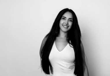 Sağlıklı, düz ve uzun siyah saçlı, mutlu bir gülümsemeyle poz veren güzel bir genç kadın.