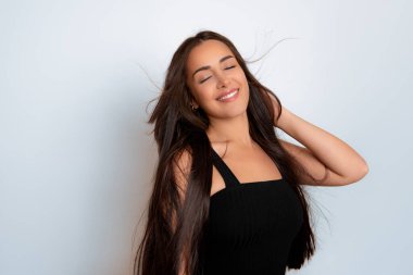 Sağlıklı, düz ve uzun siyah saçlı, mutlu bir gülümsemeyle poz veren güzel bir genç kadın.
