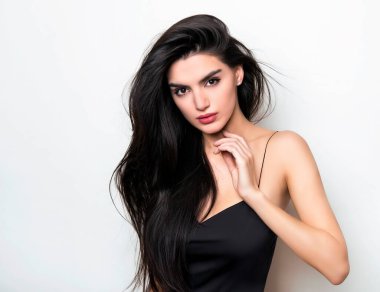 Uzun siyah ve sağlıklı saçları olan güzel bir kadın. Elbise giymiş. 