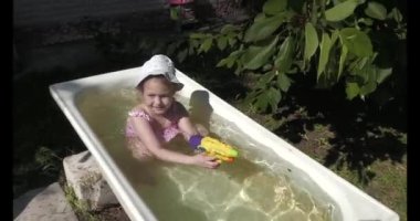 Child girl bathe in summer in a bathtub in the garden. In Visiting the village and grandparents.