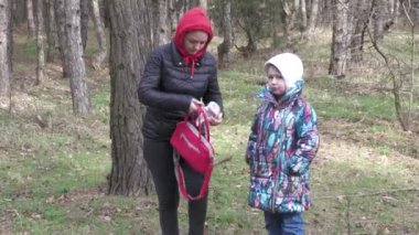 Anne ve kızı ormanda ilk bahar yürüyüşünde, ilk çiçekleri topluyor ve resim çekiyorlar..