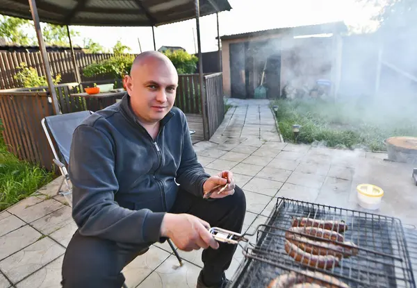 Bir adam ızgarada et pişiriyor..