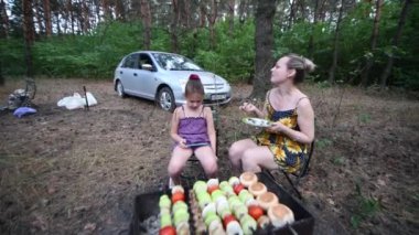 Güzel bir kadın yazın arkadaşları için ormanda şiş kebap pişirir..